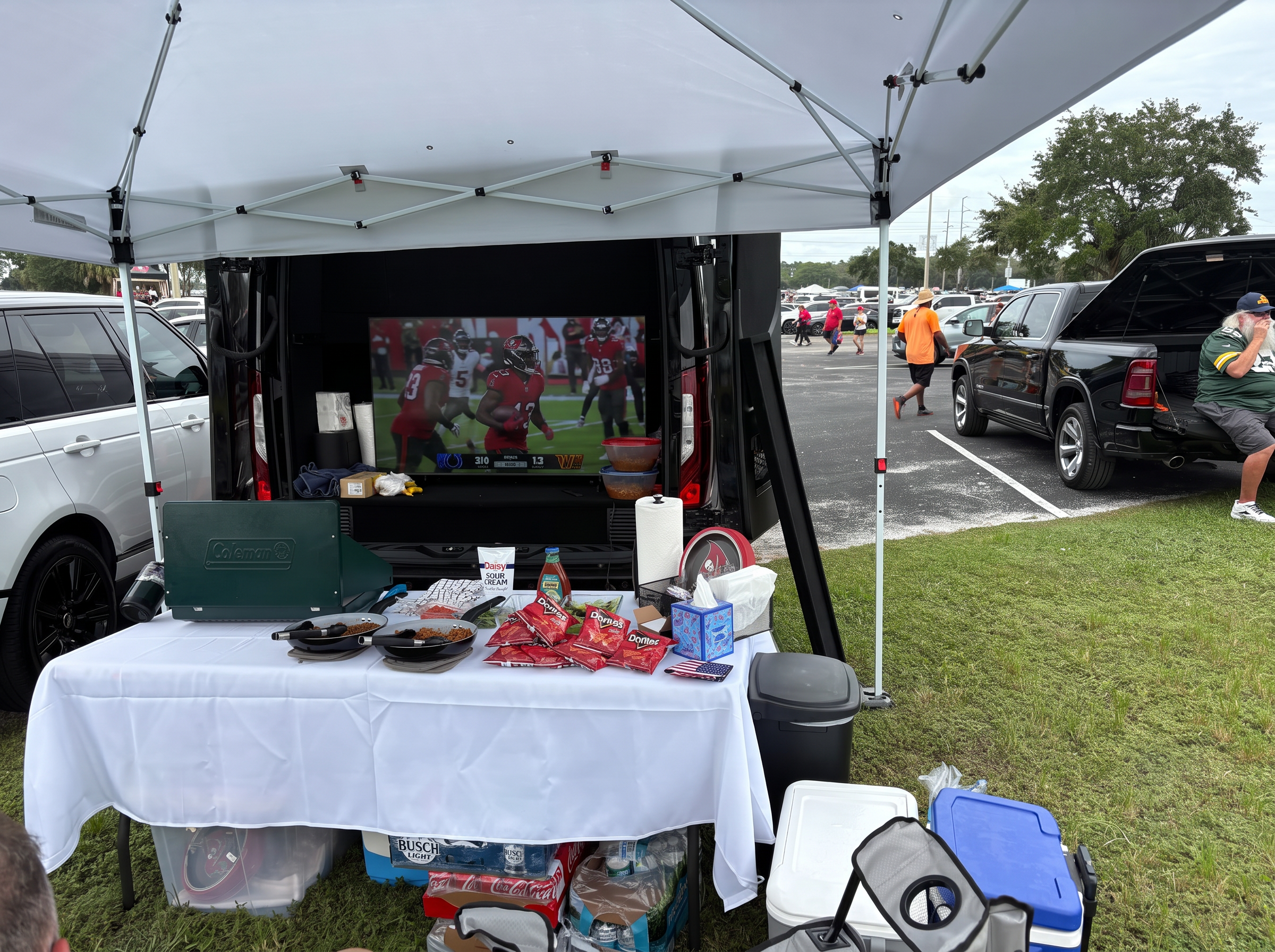 Real Lally Limo tailgate: Bucs game on the TV in the back of the Sprinter, food table and coolers under a canopy